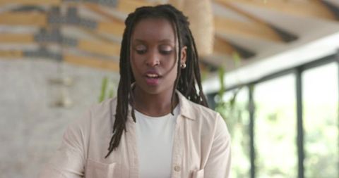 African woman reading and speaking in airy modern studio with wooden beams and plants