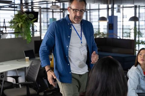 Middle-aged man leading collaborative discussion with diverse coworkers in modern office