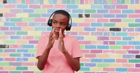 Teen Boy Joyfully Dancing with Headphones on Colorful Urban Wall