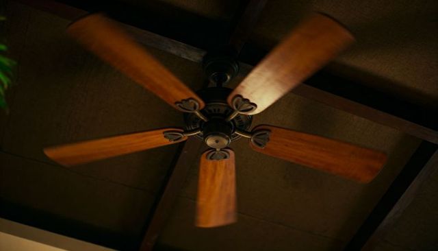 Rustic spinning ceiling fan with five wooden blades under exposed beams
