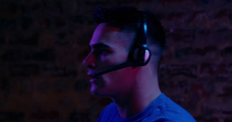 Focused Young Male Gamer Wearing Headset in Dimly Lit Room