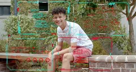 Smiling teen sitting on brick wall in urban courtyard with greenery, casual lifestyle