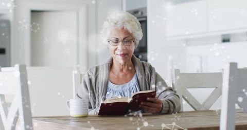 Senior Woman Enjoying Book at Modern Kitchen Table