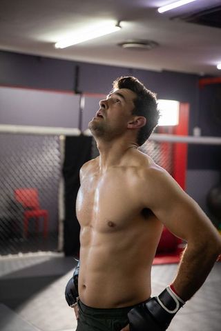 Sweaty mma fighter catching breath in cage after intense sparring session