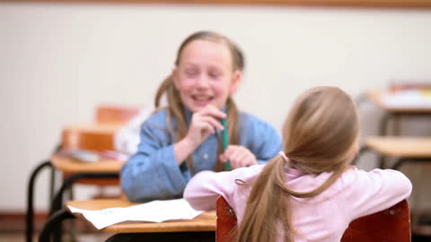 Joyful Elementary Schoolgirls Chatting in Classroom