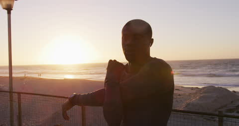 Man Stretching by Ocean at Sunset