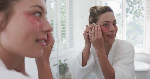 woman applying under-eye patches in modern bathroom - Download Free Stock Images Pikwizard.com