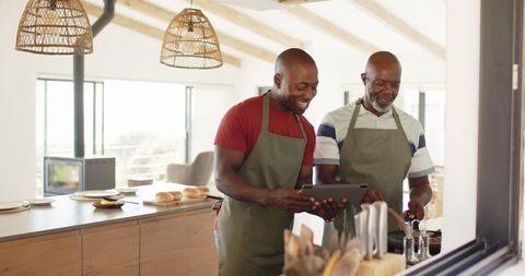 Father and son cooking together using tablet in modern kitchen