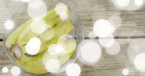 Bananas in Glass Bowl with Bokeh Lights on Rustic Wooden Table