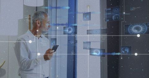 Senior man using smartphone viewing augmented reality business dashboards on office window