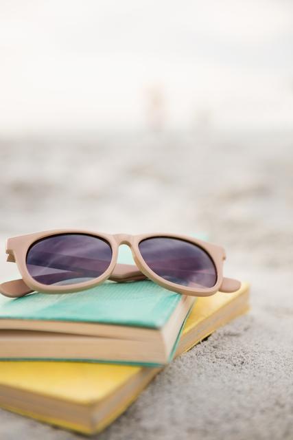 Sunglasses and books on sand at beach