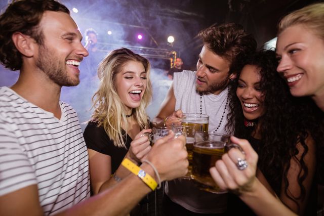 Group of friends toasting beer mugs together at a lively nightclub. Perfect for depicting nightlife, social gatherings, celebrations, and youthful enjoyment. Ideal for use in advertisements, social media posts, and articles about nightlife, friendship, and leisure activities.