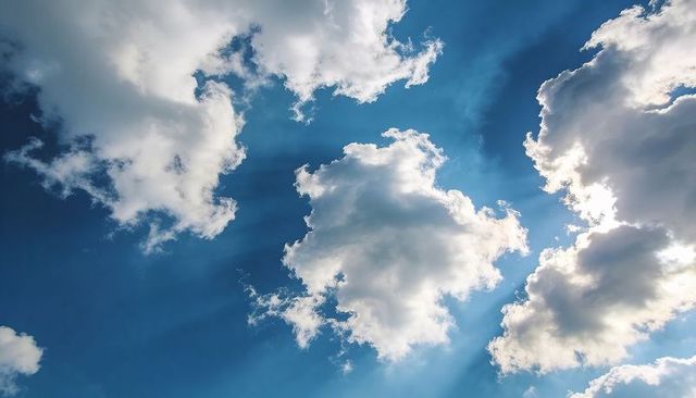 Sunlit cumulus clouds scattering crepuscular rays across vibrant blue sky, backlit glow