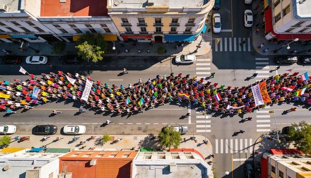 Aerial drone capturing colorful demonstration march weaving through downtown crosswalks