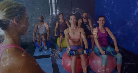 Instructor leading stability ball strength class with dumbbells and small group training