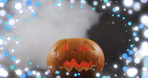 Glowing carved jack-o'-lantern casting warm light with fog and cyan hexagonal bokeh