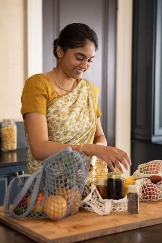 Indian Woman in Floral Sari Organizing Eco-Friendly Kitchen Essentials