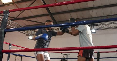 Intense sparring session between two male boxers in gym ring showing focus and technique