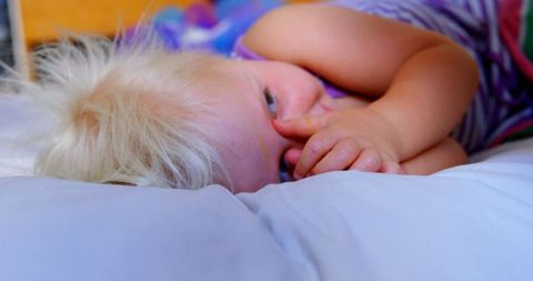 Cute Blonde Toddler Resting on Comfy Bed