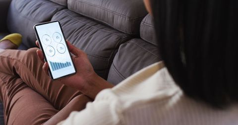 Person Analyzing Statistics on Smartphone at Home