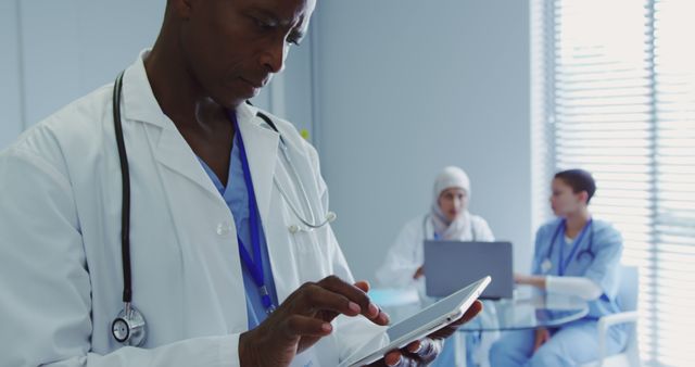 Healthcare Professional Using Tablet with Medical Team Collaborating in Background - Download Free Stock Images Pikwizard.com