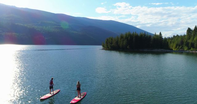 Couple Stand-Up Paddleboarding on Calm Lake with Mountain Views - Download Free Stock Images Pikwizard.com
