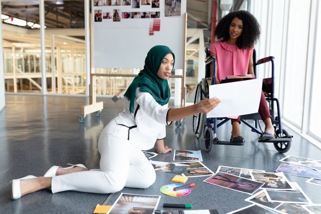Front view of diverse female graphic designers discussing on photographs in office. This is a casual creative start-up business office for a diverse team