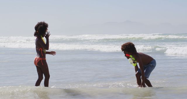 Children are enjoying a sunny day at the beach, standing in shallow ocean water with snorkeling gear. Perfect for content focused on summer activities, family vacations, outdoors fun, childhood joy, and beach destinations.