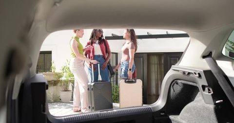 African american friends chatting with luggage by home while packing for sunny weekend getaway