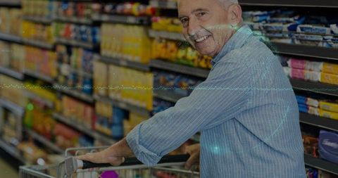 Smiling senior man pushing shopping cart in vibrant supermarket aisle, choosing groceries
