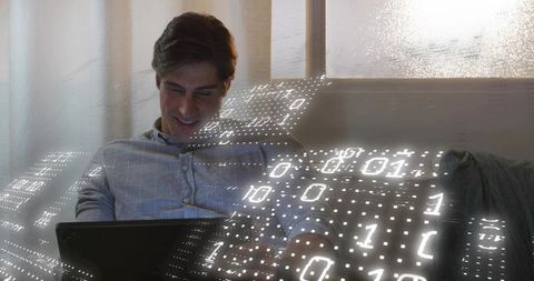 Young man lounging on couch using tablet with holographic binary data overlay