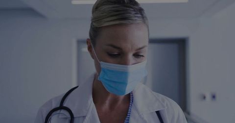 Female Doctor in Medical Uniform and Mask in Hospital Corridor