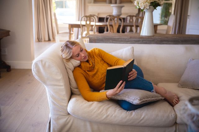 Caucasian female lying on couch, taking rest, reading book. relaxing, spending free time at home