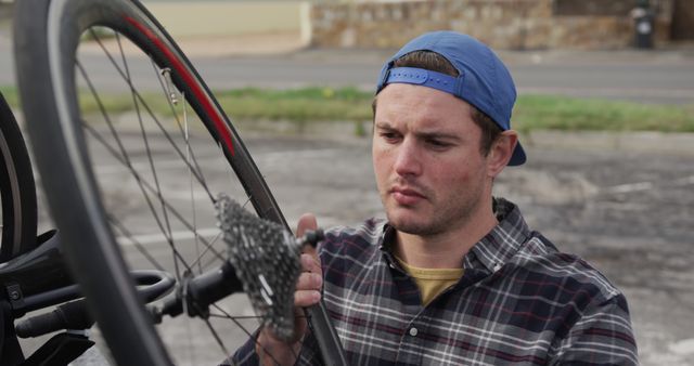 Man Wearing Plaid Shirt and Cap Fixing Bicycle - Download Free Stock Images Pikwizard.com