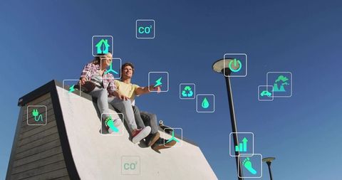 Young couple sitting on skate ramp pointing at tablet with sustainability and energy icons