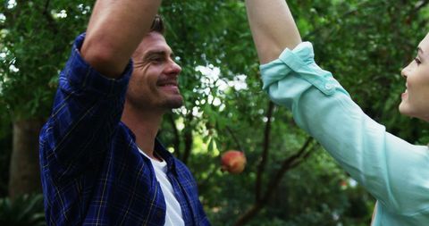 Happy Couple Enjoying Apple Picking in Lush Orchard Outdoors