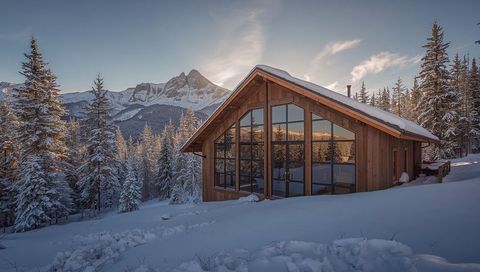 Alpine A-frame Cabin Reflecting Golden Sunset on Snow-Covered Mountain Slope