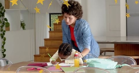 Caregiver guiding child doing homework at kitchen table helping with drawing and learning