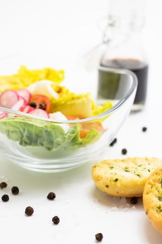 Fresh garden salad with radishes, cherry tomatoes and garlic crostini on white backdrop