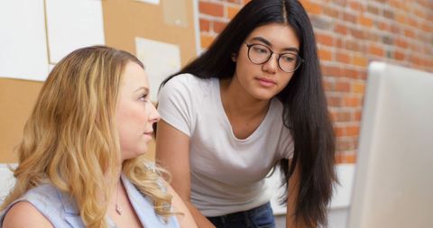 Two Women Collaborating on Office Project at Computer
