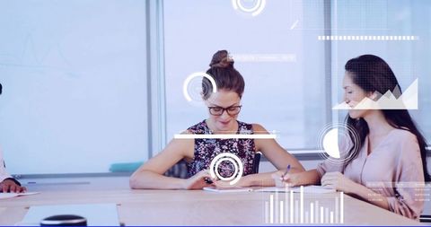 Young women collaborating at conference table with futuristic hud data overlays