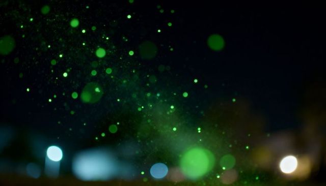 Drifting emerald bokeh orbs illuminating nocturnal urban blur