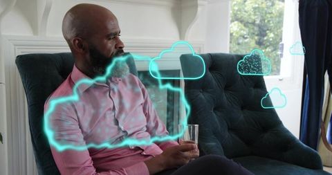 Man Relaxing on Sofa Holding Drink While Interacting with Neon Cloud Augmented Reality