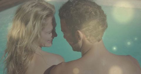 Couple in Swimwear Sharing Moment at Poolside with Sun Flare Reflections