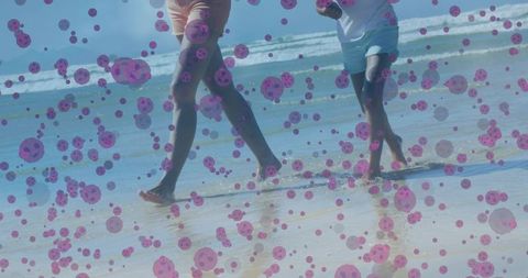 Mother and child running barefoot on sunlit beach chasing waves with purple bubble overlay