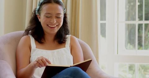 Smiling young woman reading book in cozy home environment