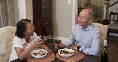 Asian Senior Couple Enjoying Dinner and Wine at Home