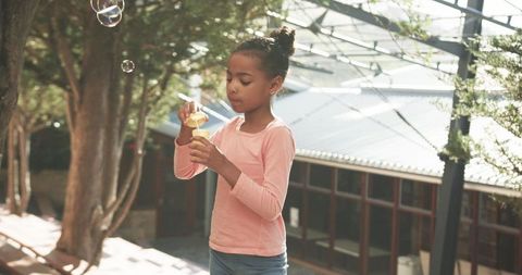 Girl blowing bubbles in tranquil outdoor setting