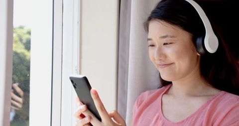 Woman Enjoying Music with Headphones while Looking at Smartphone