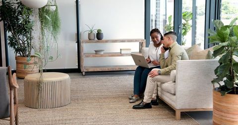 Colleagues Collaborating in Modern Office Lounge Area with Laptop